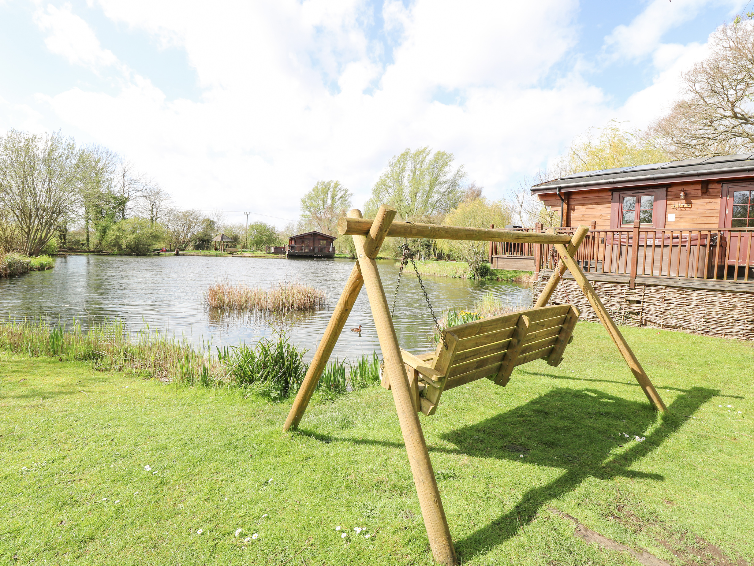 Wagtail Lodge in Badwell Ash in Suffolk. Lakeside lodge. Lovely views. Decking with hot tub and BBQ.