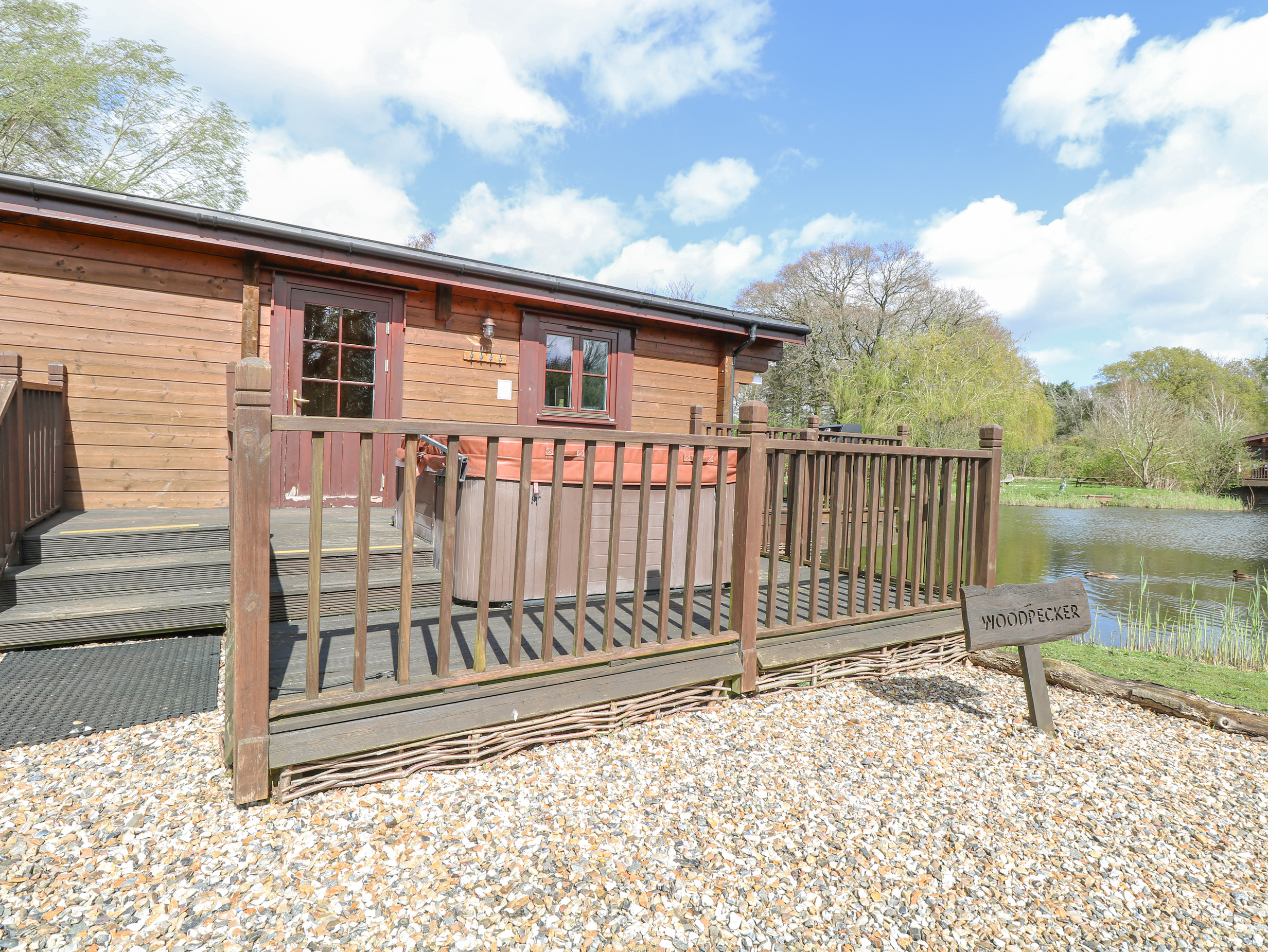 Woodpecker Lodge in Badwell Ash, Suffolk. Adults only. Decking with hot tub and BBQ. Lakeside lodge.